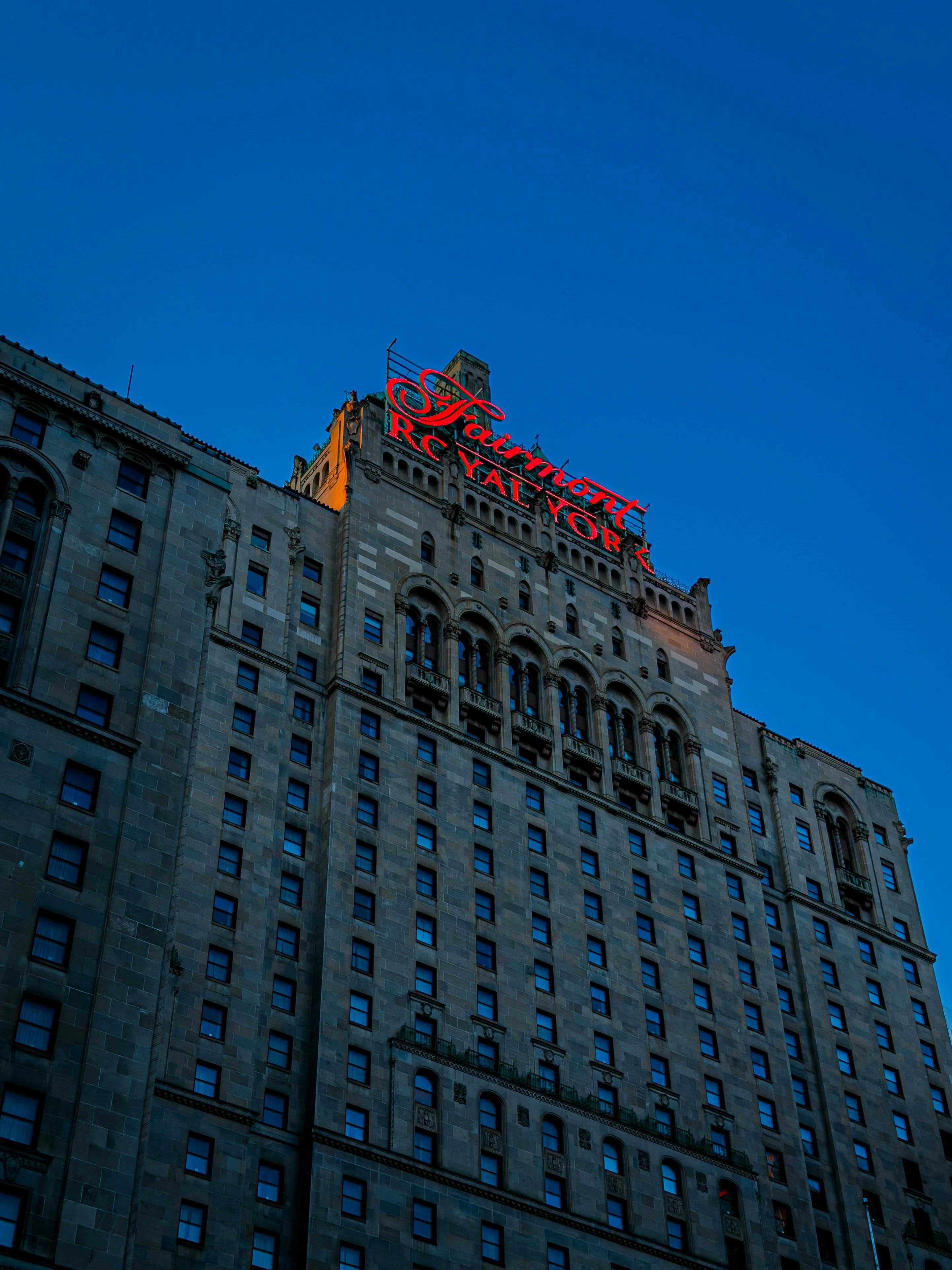 Grand historic facade and glowing red neon rooftop sign of Fairmont Royal York