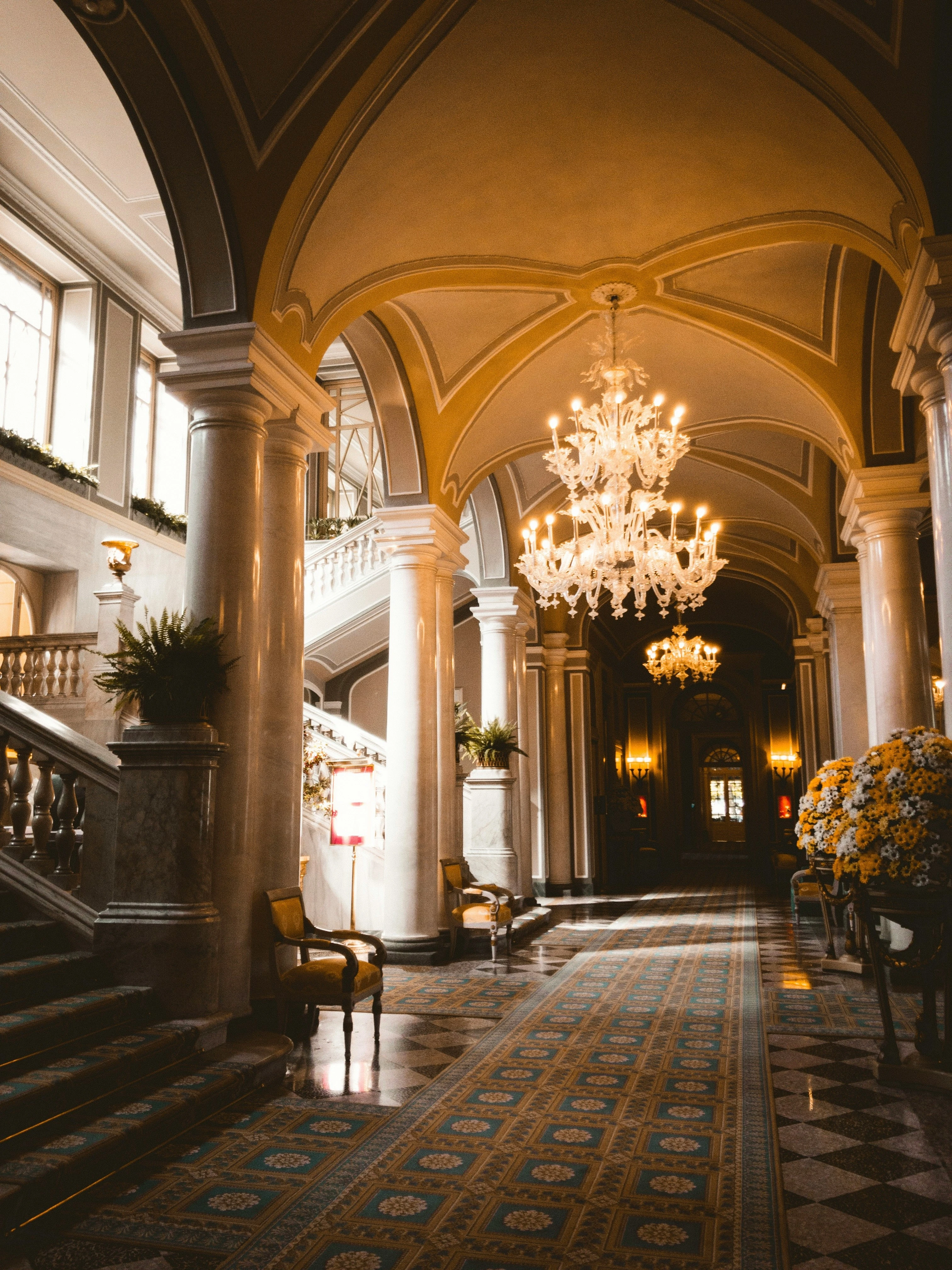 Grand luxury hotel corridor with vaulted ceilings, marble columns, and opulent crystal chandeliers