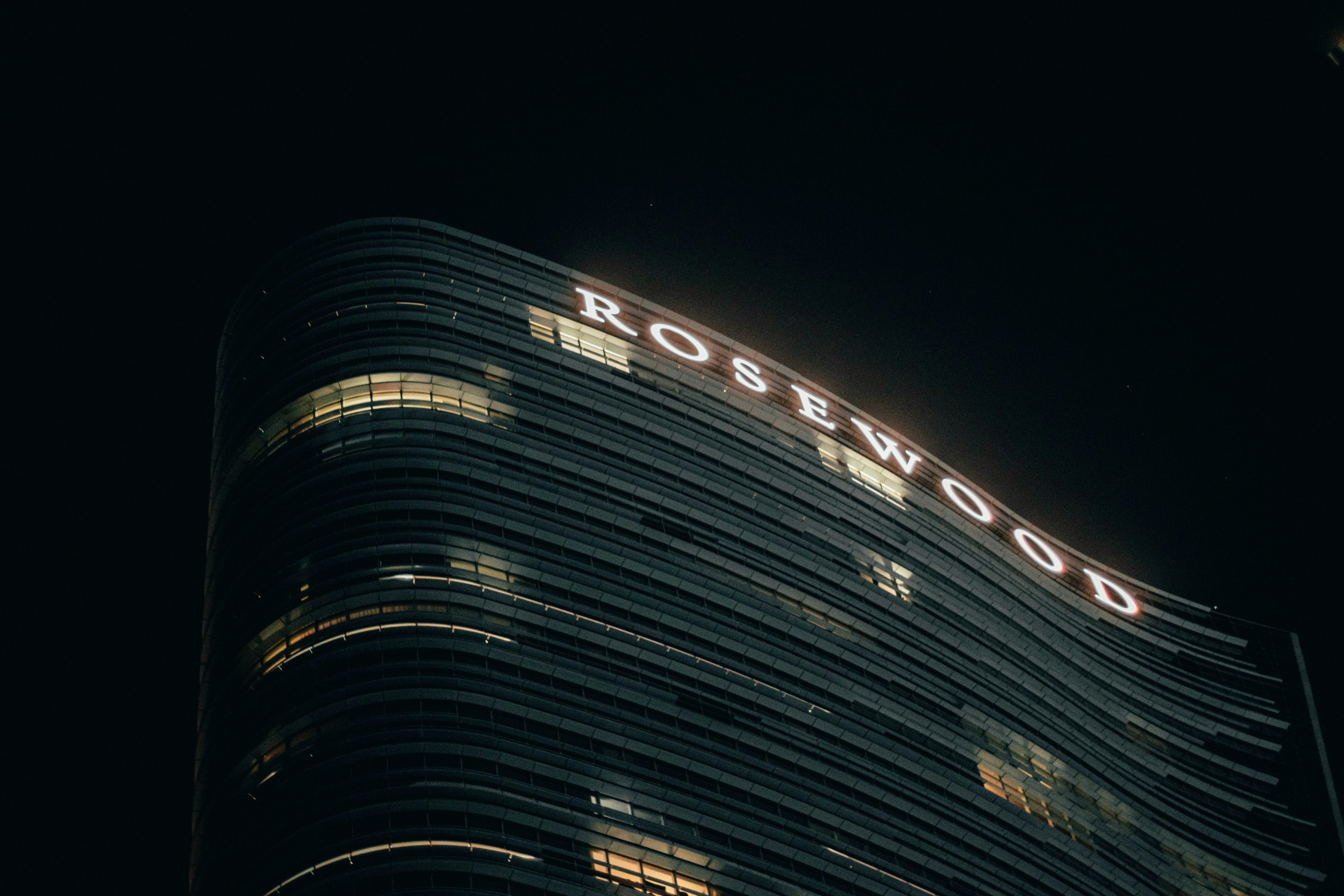 Illuminated Rosewood luxury hotel building signage against a night sky